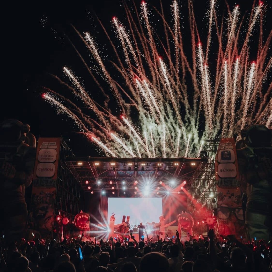 Pyrotechnics above a large stage with the crowd