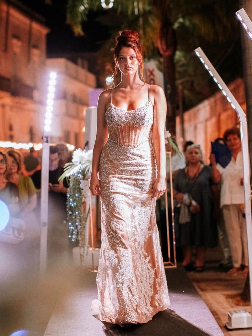 A wedding dress on a runway lit by LED bars
