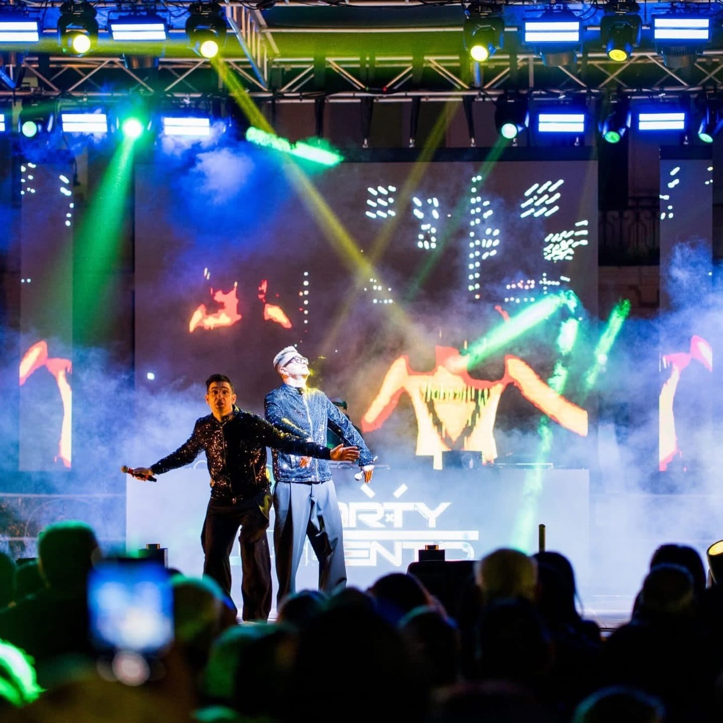 A stage with green light beams and dancers