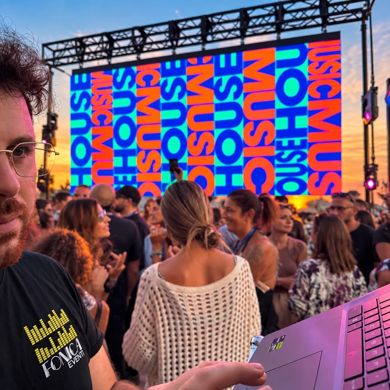 An LED wall lit above a full dance floor at sunset